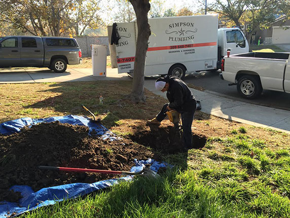 plumber digs a hole in yard in Tracy