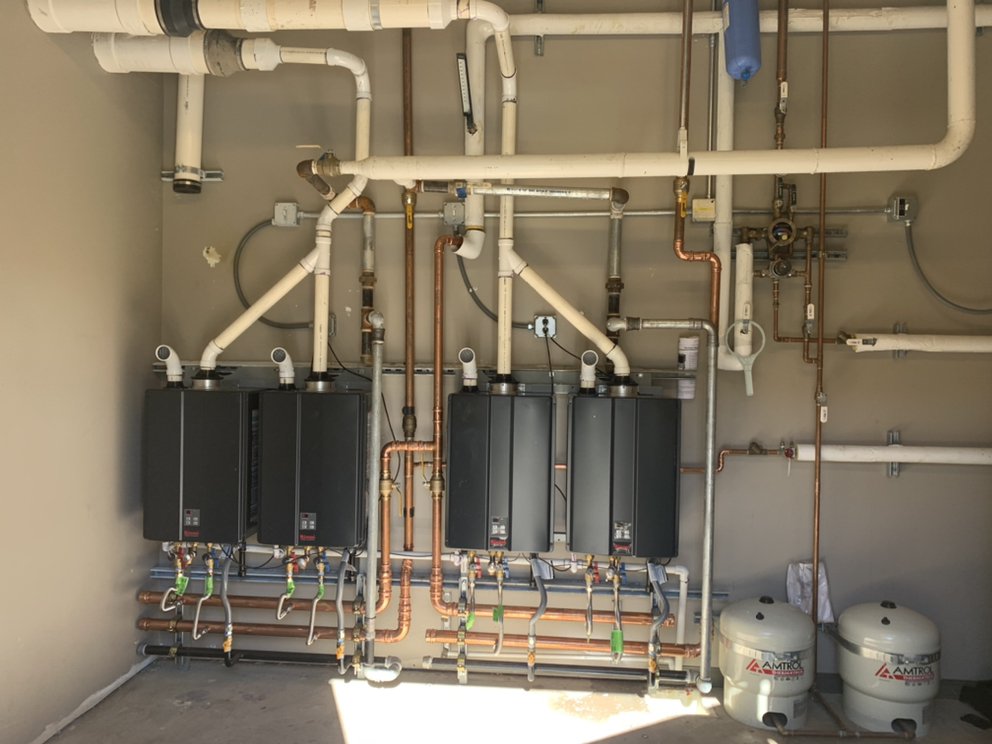 a row of four tankless water heaters being installed in a commercial building in mountain house ca by campbell roofing commercial plumbers